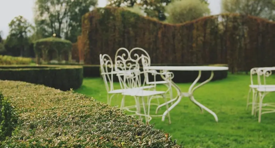 Gartenstühle auf einem Rasen, eingerahmt von geschnittenen Hecken
