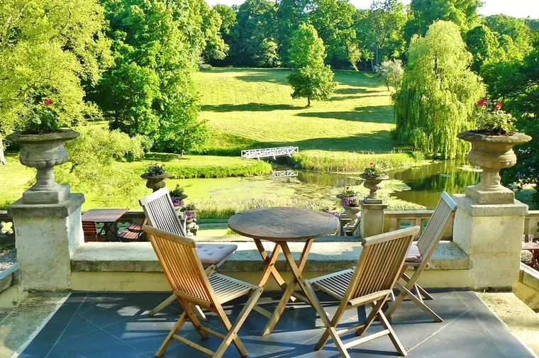 Eine Terrasse mit Tisch und Blick auf einen grünen Garten